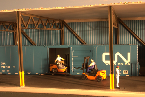 We are in the Brighton Ford Motor Plant's Transmission and Drive Train Dock.  Workers are unloading trainmissions and drivetrain parts fom the railcars.  The railroad serves two more tracks at the plant the Engine Dock, and Body Panel Dock.